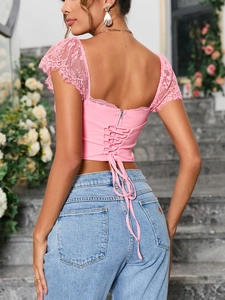Detail van roze kanten crop top met vetersluiting op de rug en wimperpantoffels mouwen