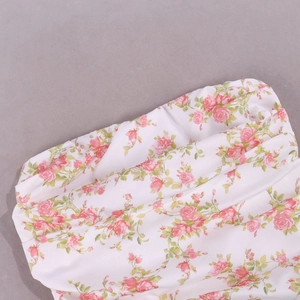 Detailed view of floral print dress featuring pink roses and pleated satin fabric