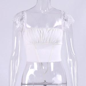 Detailweergave van witte kanten crop top met vierkante hals en gerimpelde buste