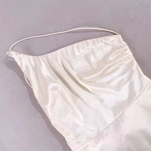 Detailed view of champagne satin fabric with delicate straps and draped neckline
