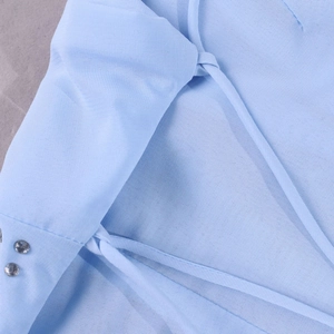 Détail d'une robe en mousseline bleu clair avec de fines bretelles et des strass argentés