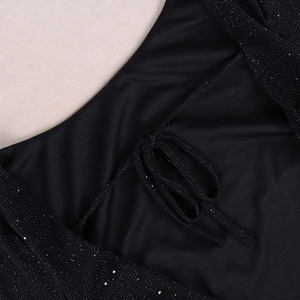 Close-up of black mesh dress featuring shimmering sequins and a delicate bow detail