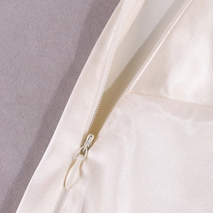 Detail of invisible zipper on cream satin backless dress with a smooth silk texture