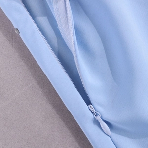 Détail de la robe en mousseline bleu clair avec fermeture éclair invisible et bouton argent