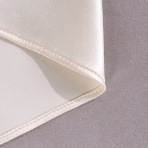 Detailed close-up of champagne satin fabric with high-quality stitching on the dress hem