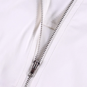 Detailopname van de zilveren metalen rits op de witte kanten crop top met vierkante hals
