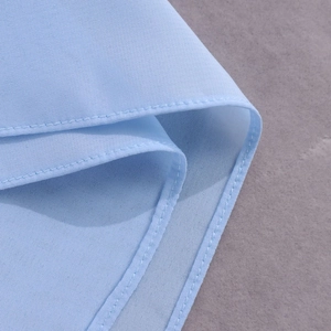 Détail du tissu en mousseline bleu clair avec couture double aiguille précise
