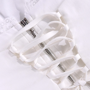 Detail van witte kanten top met metalen ritssluiting en decoratieve gekruiste veters