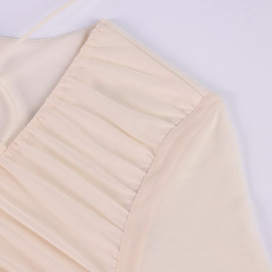 Dettaglio dell'abito in rete con cuciture arricciate sulle spalle e tessuto beige