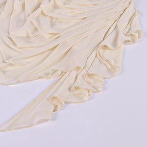 Dettaglio di volant in mesh beige chiaro e texture pieghettata su abito a maniche lunghe