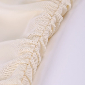 Dettaglio ravvicinato del tessuto mesh beige con dettagli a pieghe su abito sexy scollo a V