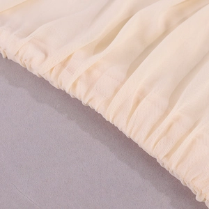 Vue macro du tissu en maille beige montrant la texture élastique plissée et la couture