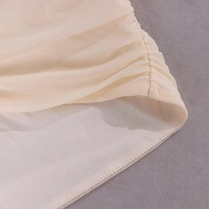 Détail du tissu en maille beige froncé montrant des coutures de qualité et une texture