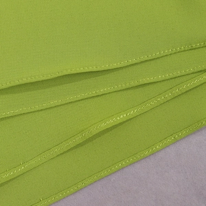 Detailed close-up of grass green chiffon fabric texture and professional hem stitching