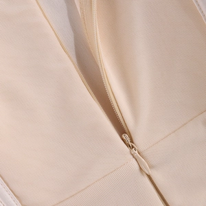Gros plan sur la fermeture éclair invisible d'une robe moulante en maille beige chic