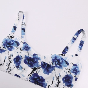 Close-up of white floral camisole top with blue roses and adjustable metal strap buckles