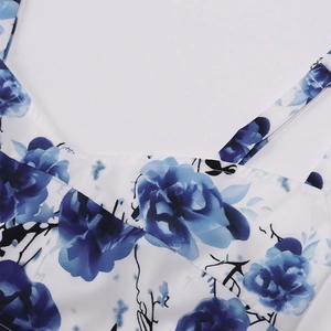 Detail of V-neckline and spaghetti straps with blue floral print on white fabric