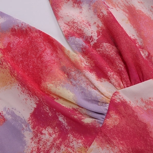 Close-up of V-neckline detail with colorful abstract print and pleated chest design on mesh dress
