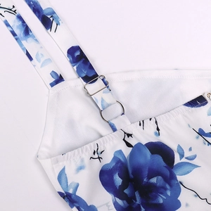 Detail of adjustable silver buckles and blue floral print on a white summer dress