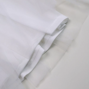 Close-up detail of tiered white mesh tulle dress hem with professional overlock stitching