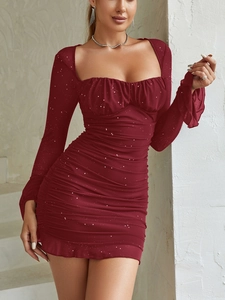 Dettaglio dell'abito aderente bordeaux con paillettes, trama a pieghe e maniche in mesh
