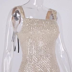 Detailed close-up of champagne sequin dress fabric with square neck and shimmering texture