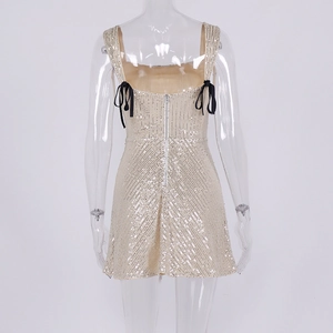 Detail view of champagne sequin dress featuring back zipper and black shoulder bow