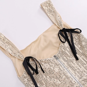 Close-up of silver sequin dress with black velvet bow straps and metal zipper detail