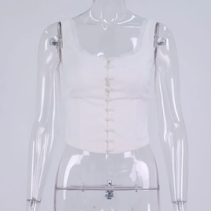 Dettaglio del corsetto bianco con bordo in pizzo, scollo quadrato e bottoni frontali