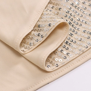 Macro shot of champagne fabric with silver sequins and stitching detail on the dress