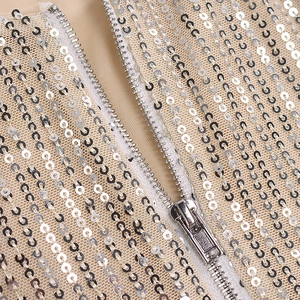 Detailed macro view of silver sequins on mesh fabric with a metallic zipper closure