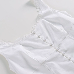 Dettaglio di un corsetto bianco con pizzo delicato e bottoni rivestiti in tessuto coordinato