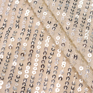 Close-up of sparkling silver sequins on champagne mesh fabric for sequin dress