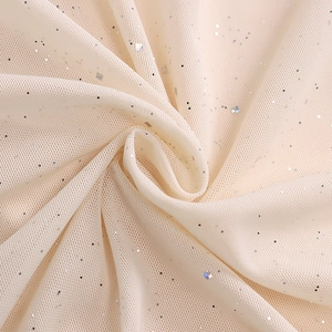 Close-up of light beige mesh fabric with shimmering silver sequins and soft drape