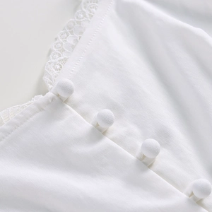 Dettaglio del corsetto bianco con bordo in pizzo e bottoni rivestiti in tessuto fine