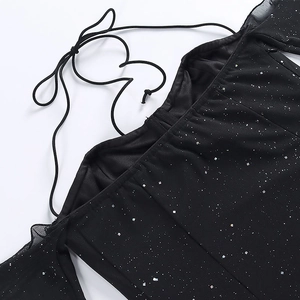 Détail d'une robe en mesh noir avec des paillettes brillantes et un col à cordon ajustable
