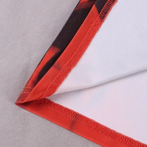 Macro shot of fine red floral print fabric with durable overlock stitching on the hem