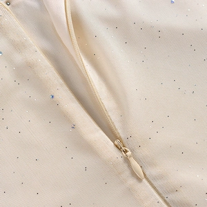 Détail de la fermeture éclair invisible sur une robe en maille beige et paillettes