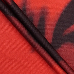 Macro detail of silky floral print fabric with vibrant red and dark brown textures