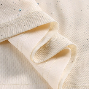 Vue détaillée du tissu mesh blanc cassé avec paillettes scintillantes et coutures soignées