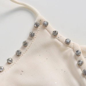 Gros plan sur tissu en maille crème avec sequins et détails en strass sur l'encolure