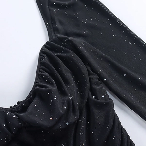 Vista dettagliata del tessuto a rete nero con paillettes argento e design arricciato