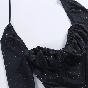 Dettaglio dell'abito in rete nera con paillettes argento e scollo drappeggiato lucido