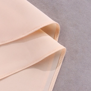 Detail view of smooth apricot chiffon fabric with neat double-stitched hem finish