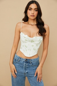 Detail of floral corset top featuring a cowl neck and structural boning on white fabric
