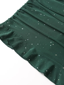 Dettaglio del tessuto a rete verde scuro con paillettes scintillanti e bordo a balze