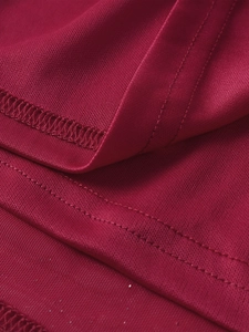 Macro d'un tissu en maille rouge foncé avec double couture et détails d'ourlet