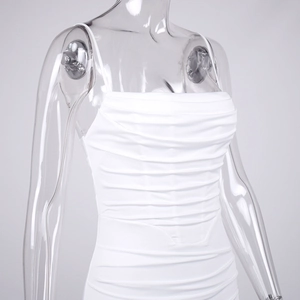 Close-up of white ruched bodycon dress showing textured fabric and thin straps on a model