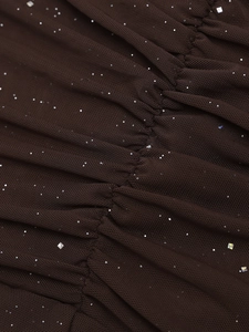Dettaglio di un abito in mesh marrone caffè con elegante drappeggio e paillettes lucide