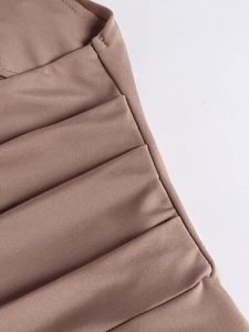 Detailed close-up of pleated silk fabric texture and neat stitching on a brown dress